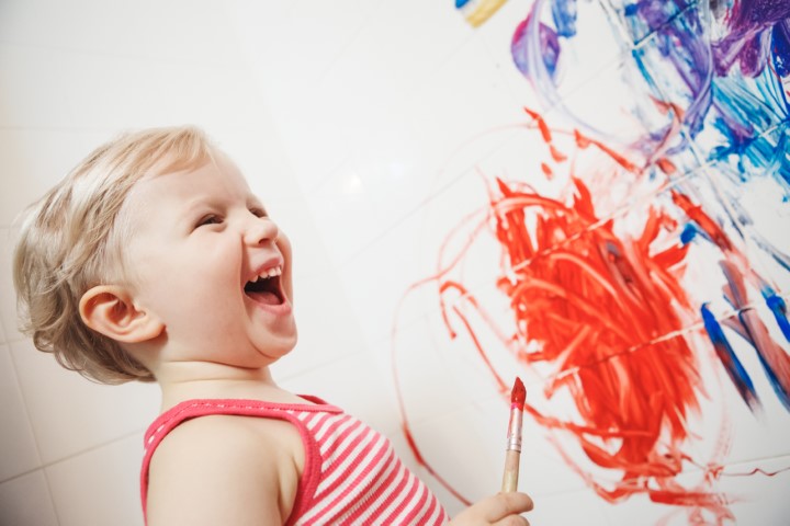 Portrait of cute adorable white Caucasian little boy girl playing and painting with paints  on wall in bathroom having fun, lifestyle childhood concept